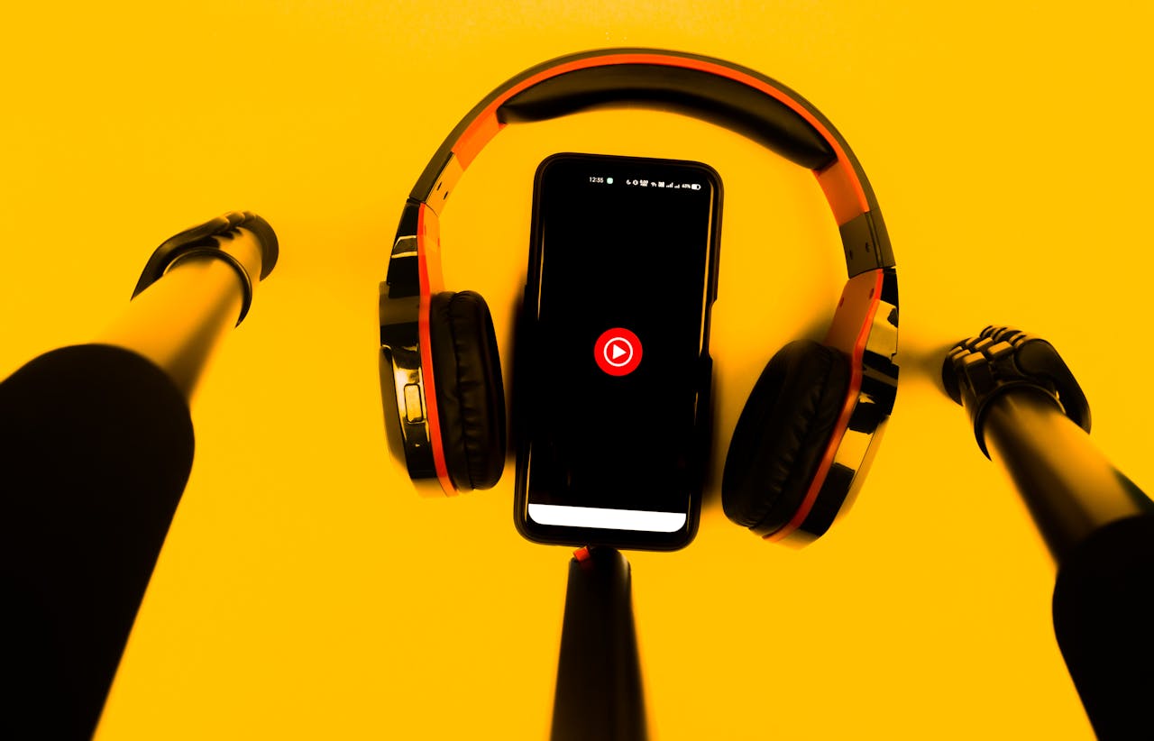 services-02 A smartphone with wireless headphones and microphone set against a vibrant yellow background.