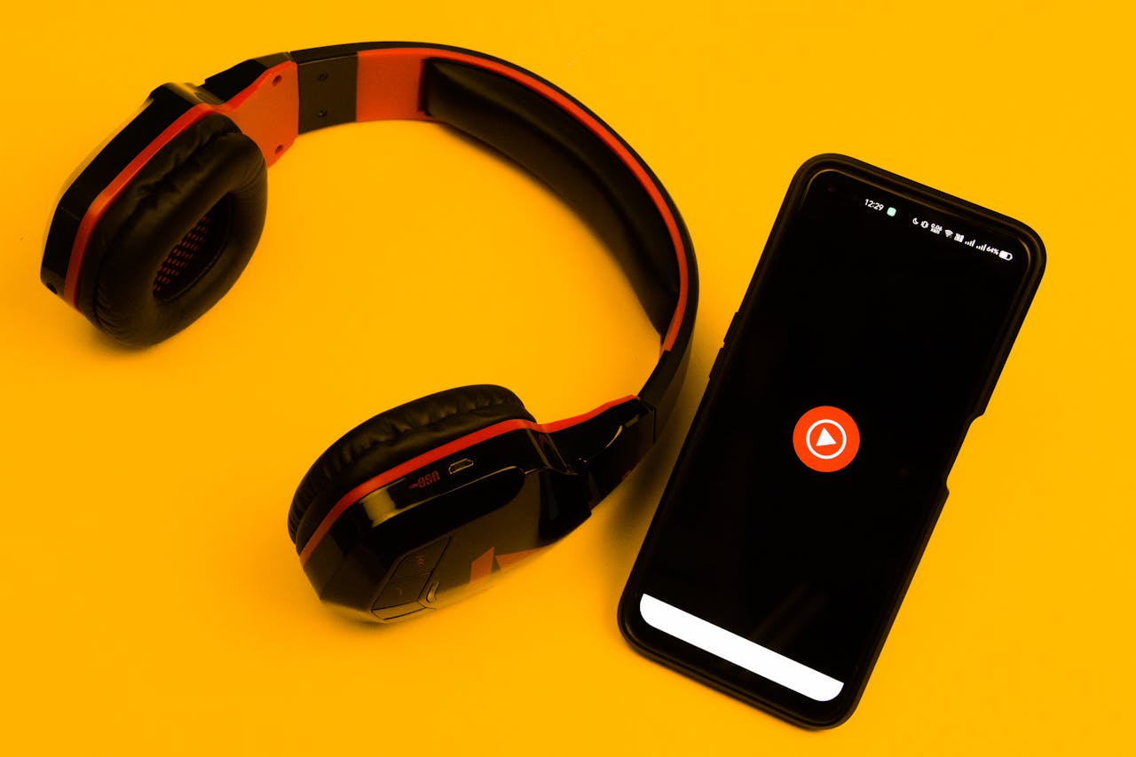 home-img Wireless headphones and smartphone with play icon on a vibrant yellow background.